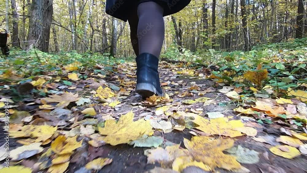 Women's feet are on the fallen autumn leaves in the forest. Slow motion video. Women's feet are on the fallen autumn leaves in the forest. Slow motion video.