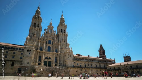 People pilgrims walking around cathedral square of Santiago de compostela on blue sky and plane trails flying background ,capital timelapse