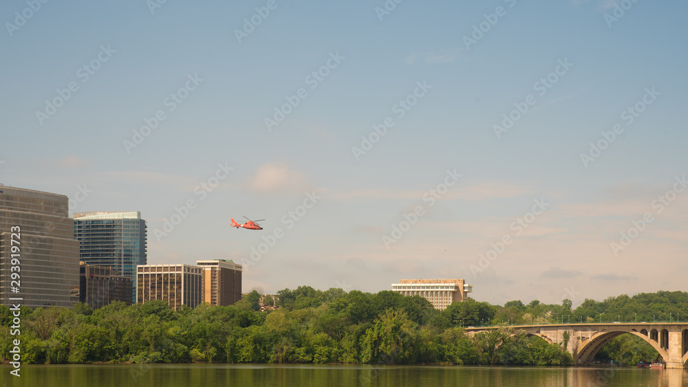 Helicopter flying over buildings on clear day with blue skies