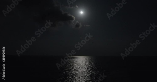 Full moon illuminates the ocean water while sailing