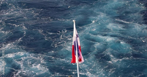 Panama flag waving in the wind with ocean water in the background.
