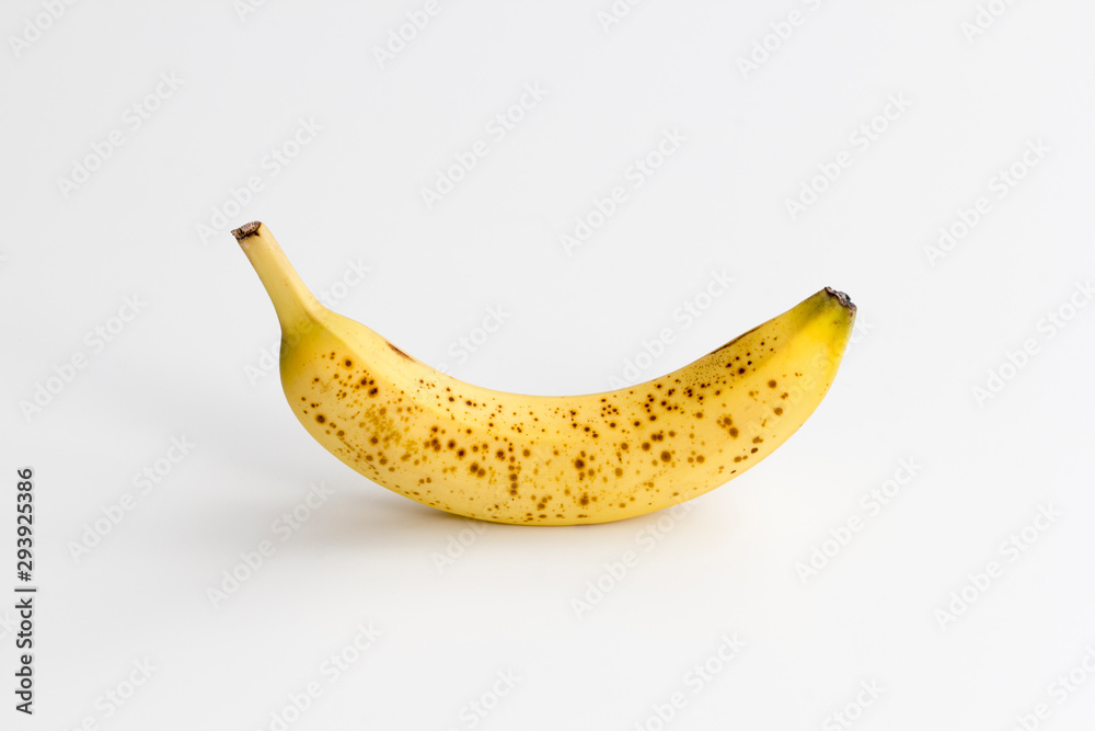 Single ripe banana with brown spots centered and isolated on a white background. Single ripe banana with brown spots centered and isolated on a white background.