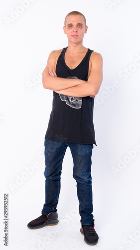 Full body shot of young bald rebellious man with arms crossed