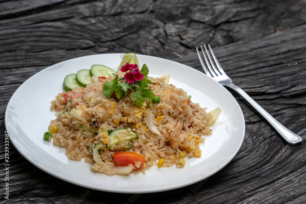 Fried rice with shrimps and vegetables in a white dish on an old wooden table, close up . Thai food , Thai cuisine