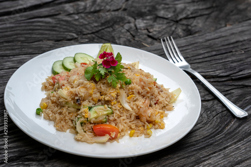 Fried rice with shrimps and vegetables in a white dish on an old wooden table, close up . Thai food , Thai cuisine