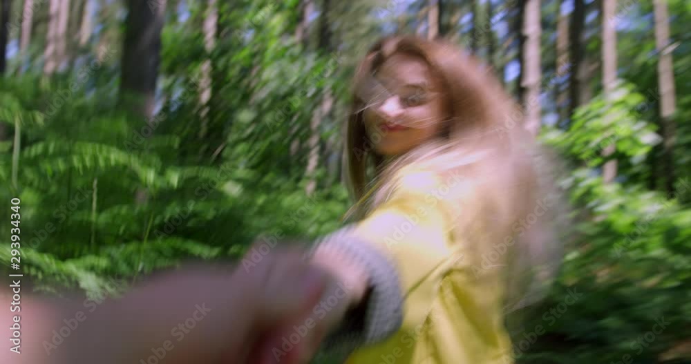 Blonde Young Woman Holding Hands with Boyfriend in a Nature Forest. Traveller Girl wearing Yellow Rain coat in Tree lined Woodland setting. British Tourism National Trust Reserve Blonde Young Woman Holding Hands with Boyfriend in a Nature Forest. Traveller Girl wearing Yellow Rain coat in Tree lined Woodland setting. British Tourism National Trust Reserve