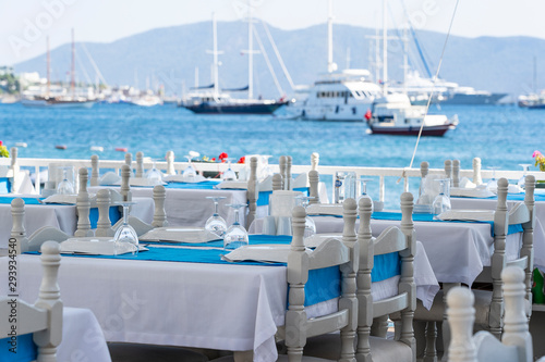 Elegant table setting with fork  knife  wine glass  white plate and blue napkin in restaurant . Nice dining table set with arranged silverware and napkins for dinner