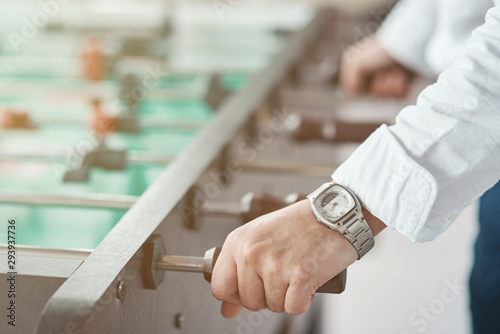 Close up shot of man's hands. Office male worker enjoying table soccer game during his free time at the workplace. Selective focus on hand. Horizontal shot