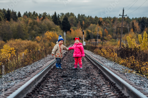 Boy and girl play on the railroad tracks in autumn day