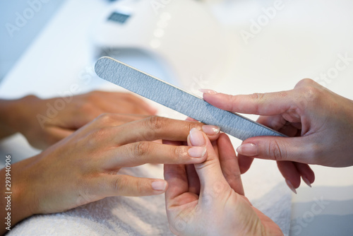 Woman in a nails salon receiving a manicure with nail file