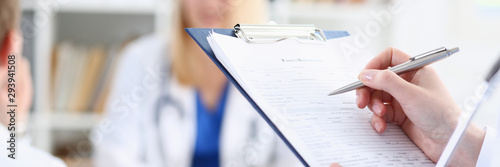 Female medicine doctor hand holding silver pen looking in clipboard pad closeup. Ward round patient visit check 911 medical calculation and statistics concept. Physician ready to examine patient