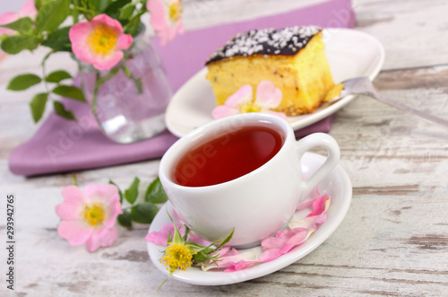 Cup of tea with cheesecake and wild rose flower