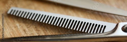 Thinning shears lie on wooden table in hair salon closeup. Stylish hairstyle concept background.