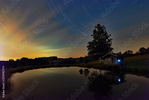 Nächtliche Sternenlaufbahn über einem See in Niederbayern, Bayern, Deutschland 