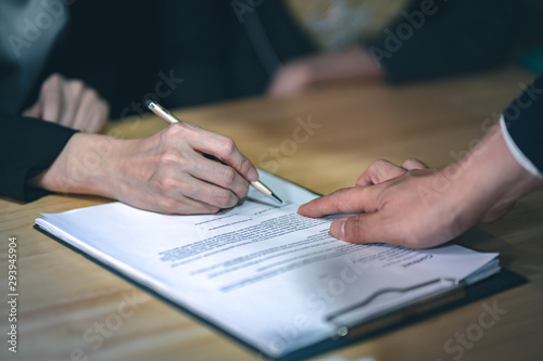 Business contract signing - Man pointing at the bottom at the contract for a woman for signature.