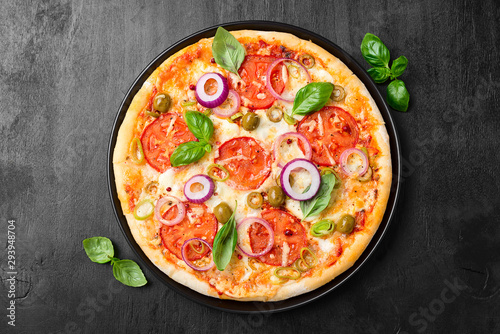  Italian pizza with melted mozzarella cheese green olives and tomato garnished with fresh vegetables and basil leaves.