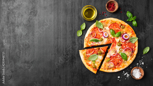  Italian pizza with melted mozzarella cheese green olives and tomato garnished with fresh vegetables and basil leaves.