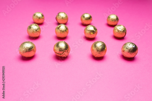 Chocolates in a multi-colored foil on a pink background