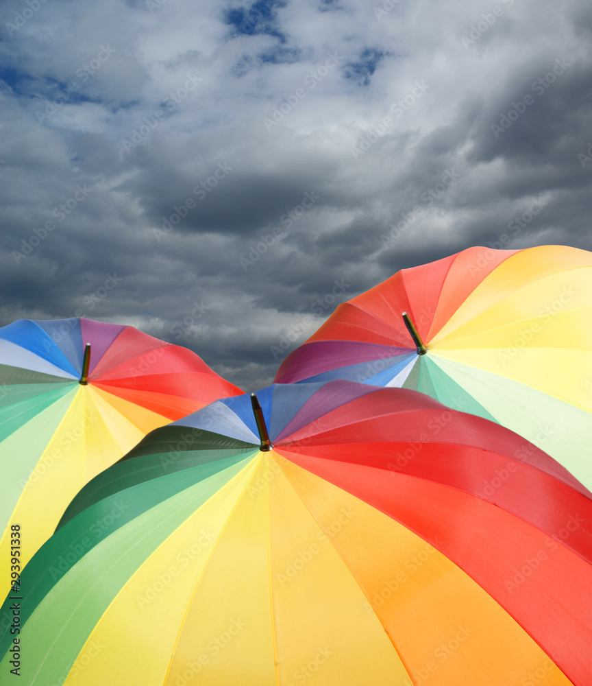 Rainbow umbrellas on dramatic sky background