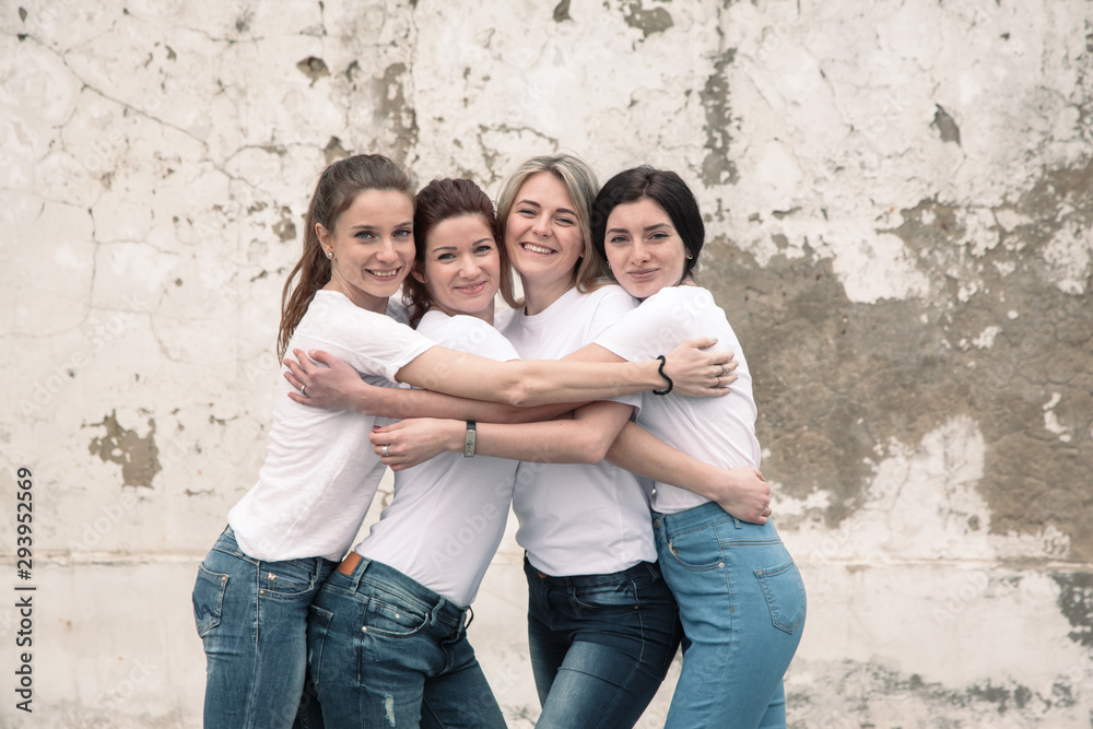 Group of diverse girls in tshirts and jeans over street wall
