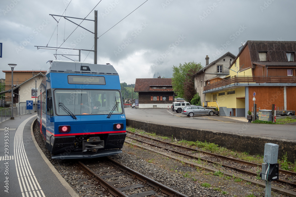 Blue train stop at the station in Meiringen rural area of switzerland on cloudy sky background with copy space