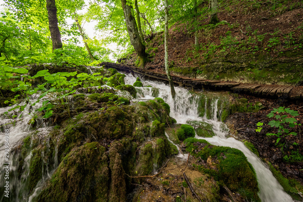 Wooden walkway bridging cascades of water rushing down mossy rocks at the Plitvice Lakes National Park in Croatia Wooden walkway bridging cascades of water rushing down mossy rocks at the Plitvice Lakes National Park in Croatia
