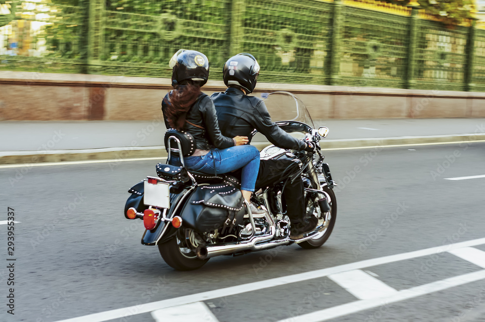 a man drives a girl on his black motorcycle