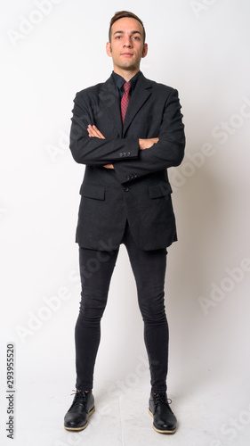 Full body shot of young Persian businessman in suit with arms crossed