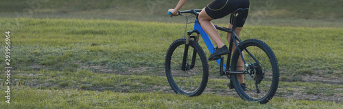 Girl on a mountain bike on offroad, beautiful portrait of a cyclist at sunset, Fitness girl rides a modern carbon fiber mountain bike in sportswear. Close-up portrait of a girl in a helmet and glasses