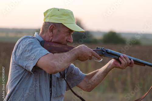 Hunting period, autumn season open. A hunter with a gun in his hands in hunting clothes in the autumn forest in search of a trophy. A man stands with weapons and hunting dogs tracking down the game. 