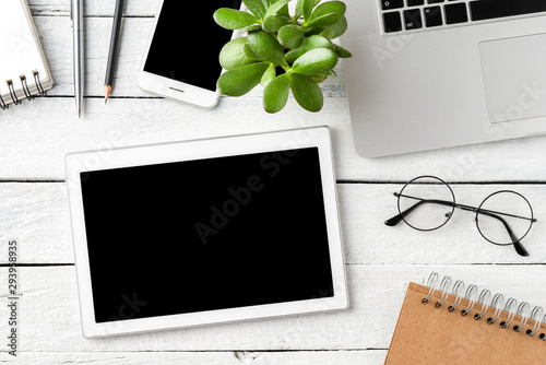 Digital tablet with empty screen on white wooden background with business accessories. Office desktop