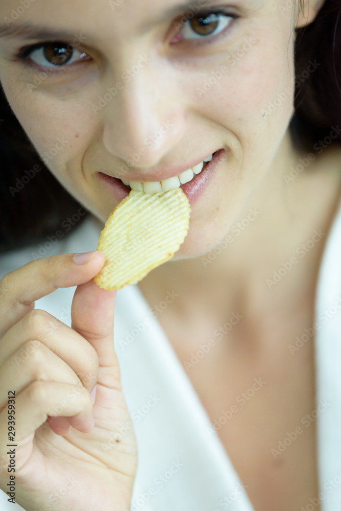 A beautiful woman wearing a towel and a white bathrobe has to eat a snack potato with happy and relaxing on the bed at a condominium in the morning. A beautiful woman wearing a towel and a white bathrobe has to eat a snack potato with happy and relaxing on the bed at a condominium in the morning.