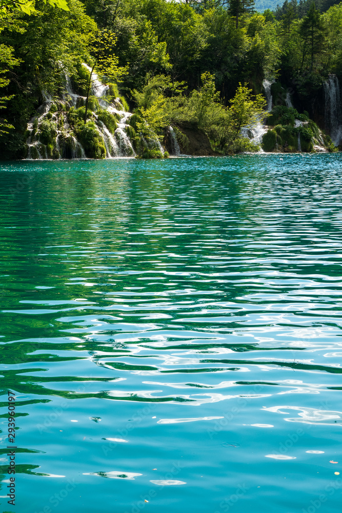 Rushing water cascades down the natural barriers into the crystal clear and azure coloured Lake Milanovac at the Plitvice Lakes National Park, Croatia