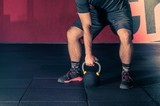 functional training with Kettle Bells Kettlebells, a young sports guy preparing to lift weights in the gym, the concept of a healthy lifestyle and functional training