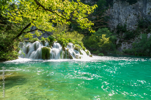 Fototapeta Naklejka Na Ścianę i Meble -  Rushing water cascades down the natural barriers into the crystal clear and azure coloured Lake Gavanovac at the Plitvice Lakes National Park, Croatia