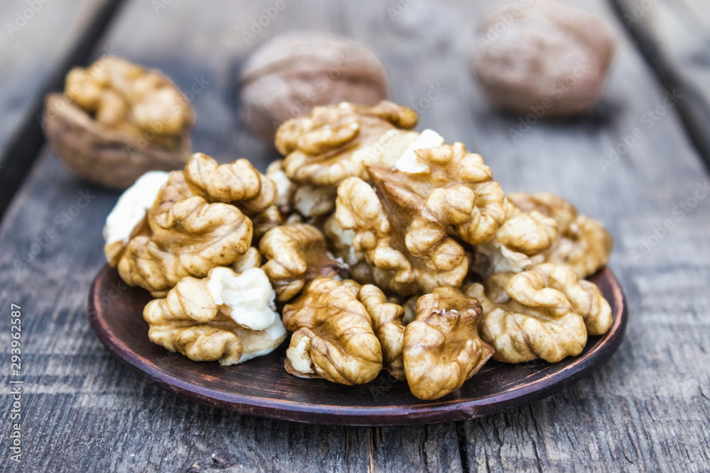 Walnut kernels lie in a bowl on a rustic old wooden table. Fresh walnuts. Walnut kernels lie in a bowl on a rustic old wooden table. Fresh walnuts.