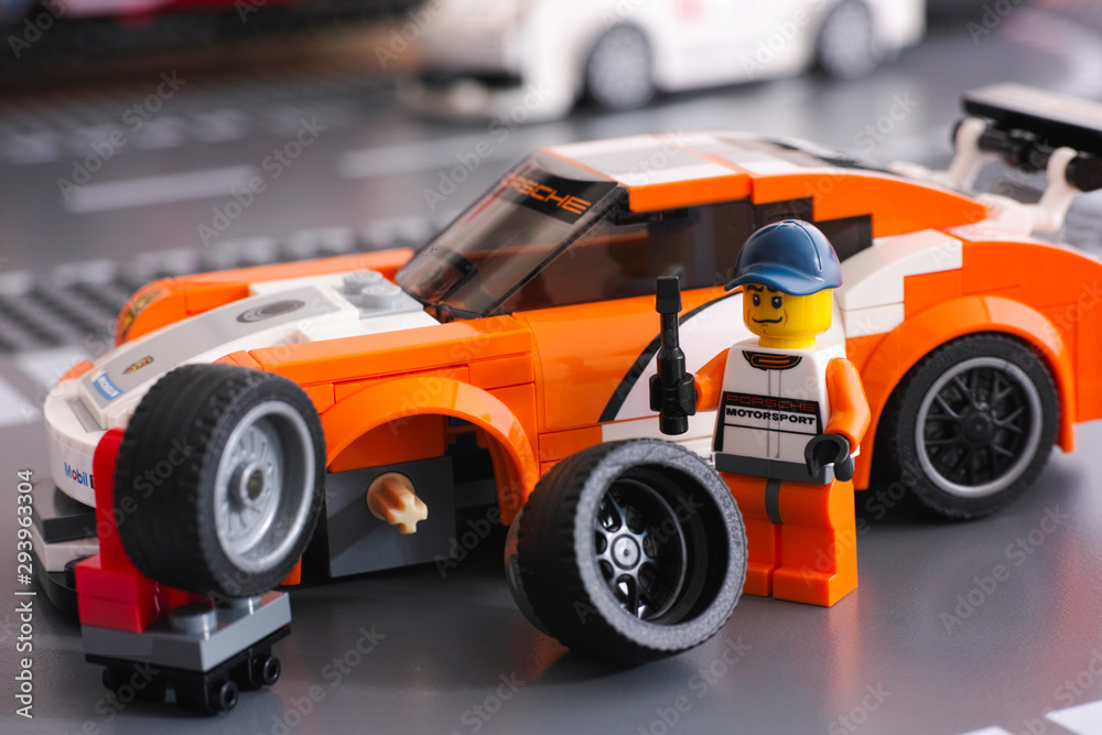 Tambov, Russian Federation - June 26, 2015 Lego driver minifigure is fixing  wheel of Porsche 911 GT by LEGO Speed Champions on the Lego road  baseplates. Studio shot. Stock Photo | Adobe Stock