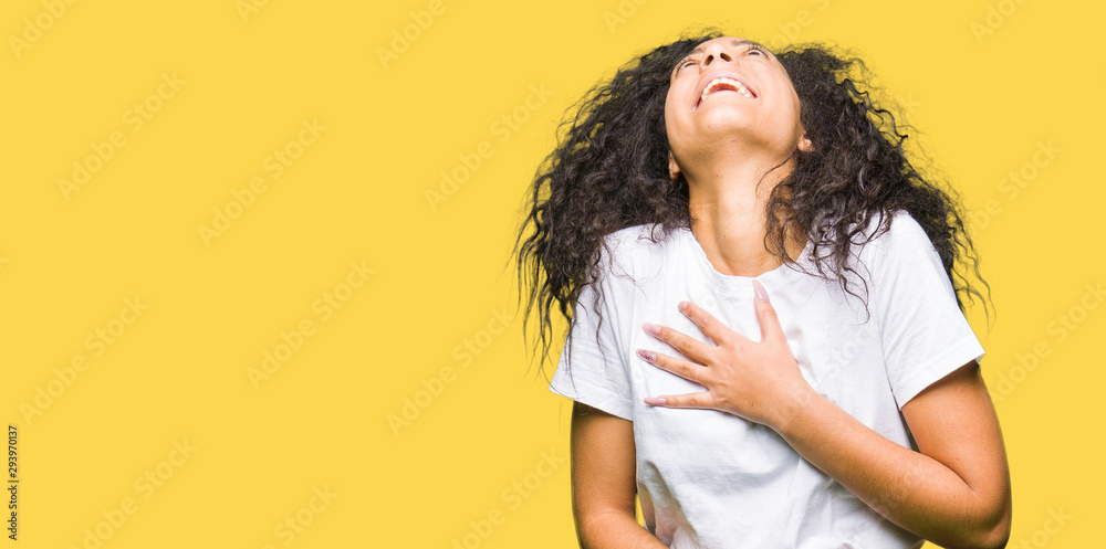 Young beautiful girl with curly hair wearing casual white t-shirt Smiling and laughing hard out loud because funny crazy joke. Happy expression. Young beautiful girl with curly hair wearing casual white t-shirt Smiling and laughing hard out loud because funny crazy joke. Happy expression.