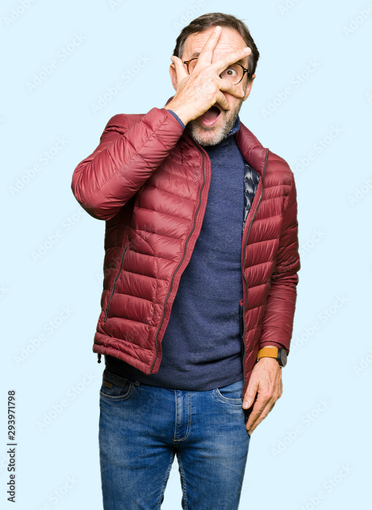 Middle age handsome man wearing glasses and winter coat peeking in shock covering face and eyes with hand, looking through fingers with embarrassed expression. Middle age handsome man wearing glasses and winter coat peeking in shock covering face and eyes with hand, looking through fingers with embarrassed expression.