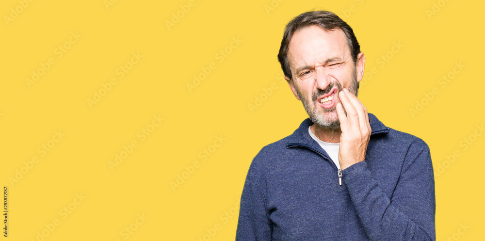 Middle age handsome man wearing a sweater touching mouth with hand with painful expression because of toothache or dental illness on teeth. Dentist concept. Middle age handsome man wearing a sweater touching mouth with hand with painful expression because of toothache or dental illness on teeth. Dentist concept.
