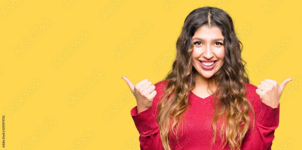 Young beautiful woman wearing red sweater success sign doing positive gesture with hand, thumbs up smiling and happy. Looking at the camera with cheerful expression, winner gesture. Young beautiful woman wearing red sweater success sign doing positive gesture with hand, thumbs up smiling and happy. Looking at the camera with cheerful expression, winner gesture.