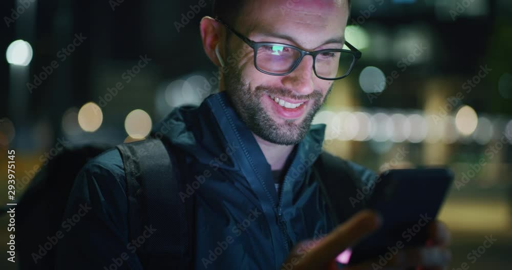 Slow motion close up of young man is using mobile phone in a center of the city by night.