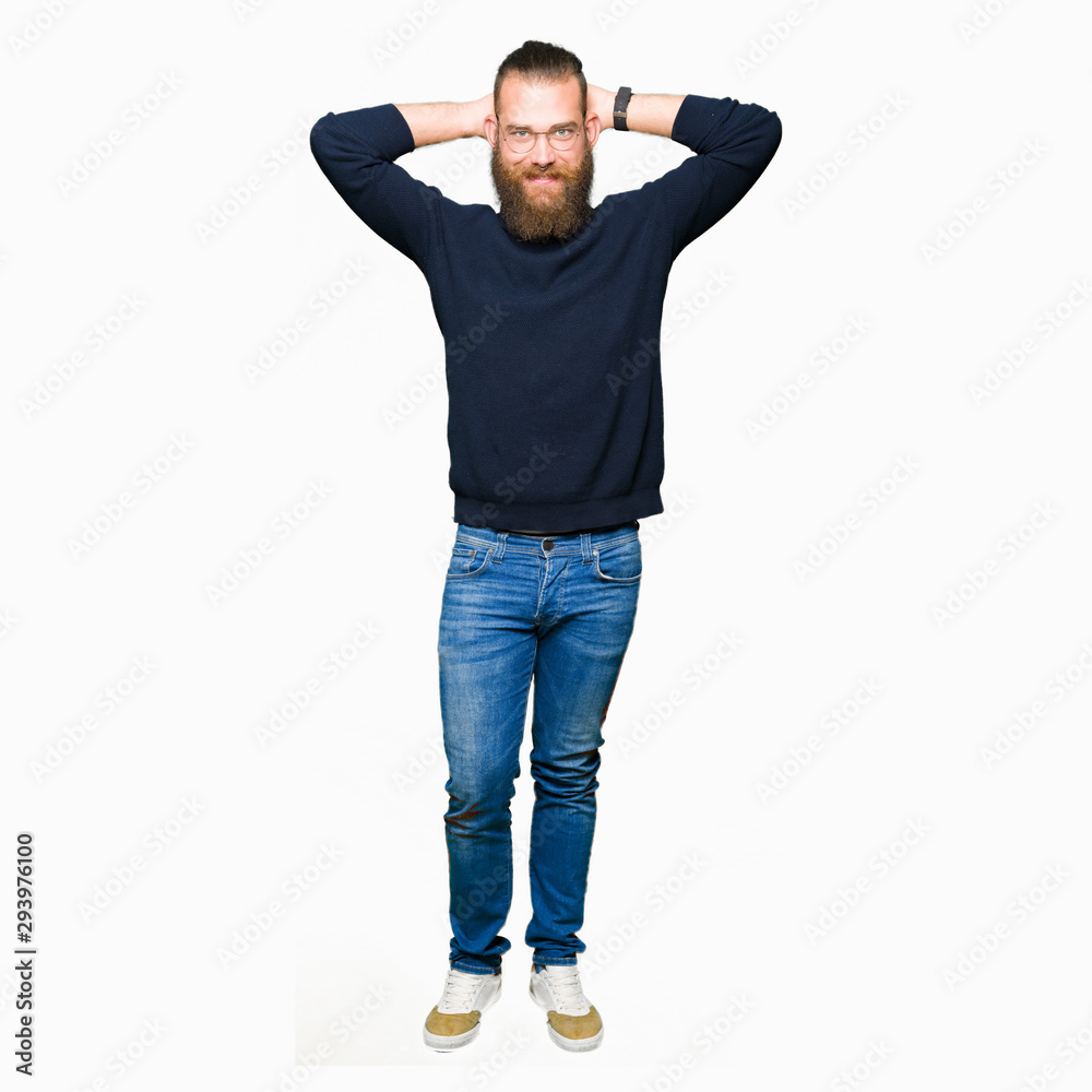 Young blond man wearing glasses and turtleneck sweater Relaxing and stretching with arms and hands behind head and neck, smiling happy Young blond man wearing glasses and turtleneck sweater Relaxing and stretching with arms and hands behind head and neck, smiling happy