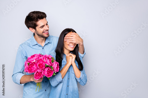 Photo of charming cute nice fascinating couple of two people spending time together with boyfriend intending to gift her bouquet and her anticipating with eyes covered isolated white grey background
