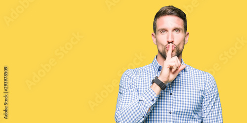 Handsome business man with blue eyes asking to be quiet with finger on lips. Silence and secret concept.