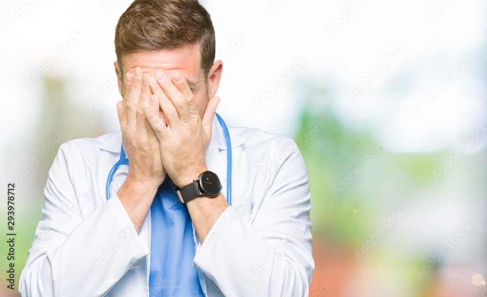 Handsome doctor man wearing medical uniform over isolated background with sad expression covering face with hands while crying. Depression concept.