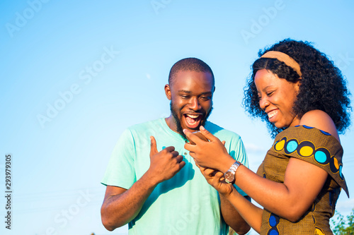 satisfied boyfriend and girlfriend checking interesting content on their mobile phone, celebrating  after receiving salary notification 