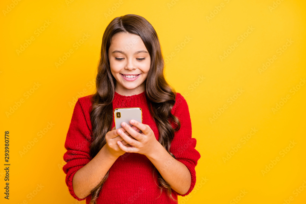 Portrait of positive cheerful wavy long hair model child use her cellphone read feednews blog posts feel content chilling have rest relax wear style pullover isolated over yellow color background Portrait of positive cheerful wavy long hair model child use her cellphone read feednews blog posts feel content chilling have rest relax wear style pullover isolated over yellow color background