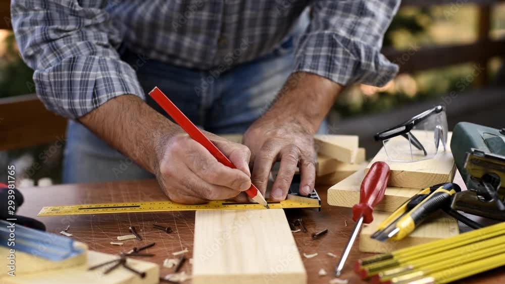 Adult carpenter craftsman with a pencil and the carpenter's square trace the cutting line on a wooden table. Construction industry, housework do it yourself. Footage.