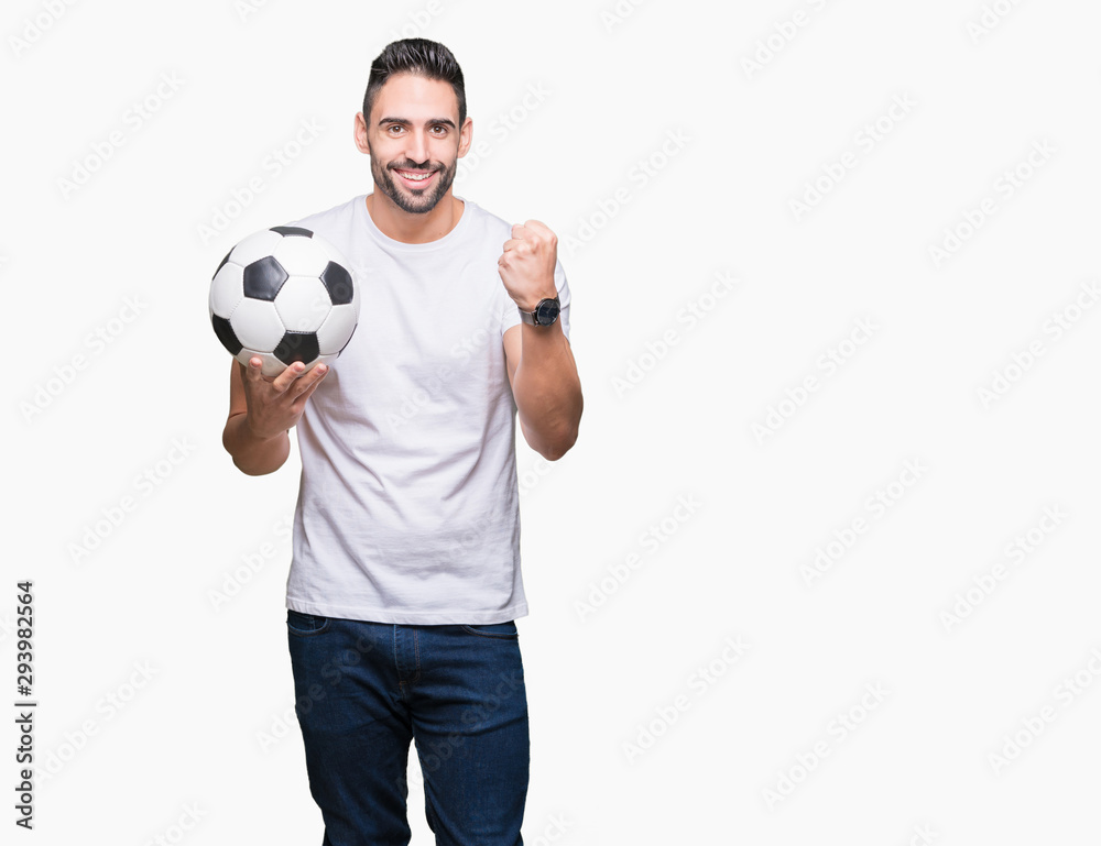 Young man holding soccer football ball over isolated background screaming proud and celebrating victory and success very excited, cheering emotion